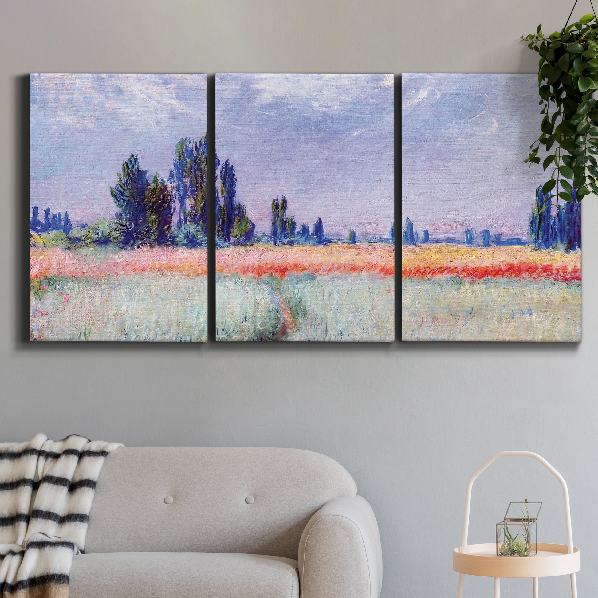 Three-panel canvas wall art featuring flowering field with poppies, displayed in a modern living room above a sofa.
