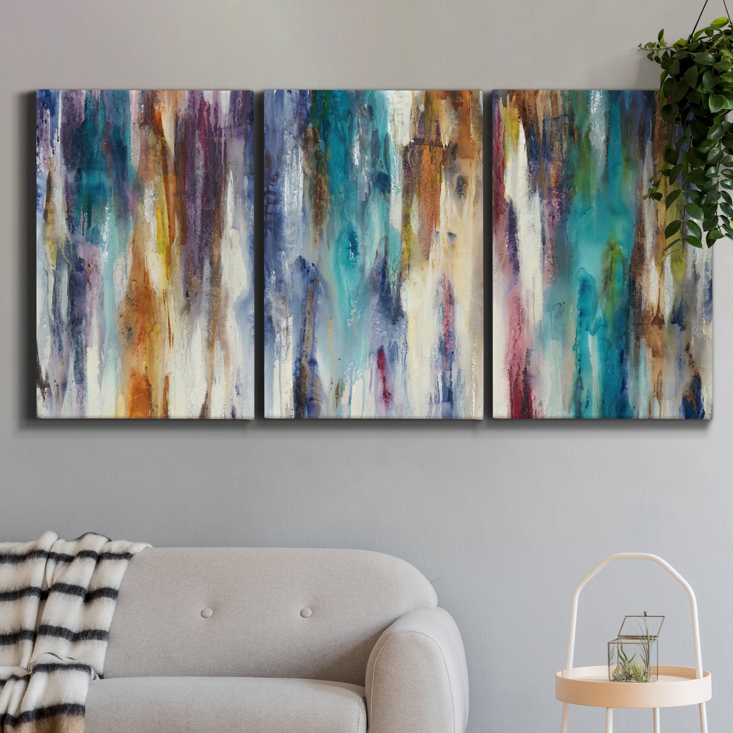 Three-panel canvas wall art featuring abstract shifting color forms, displayed in a modern living room above a sofa.
