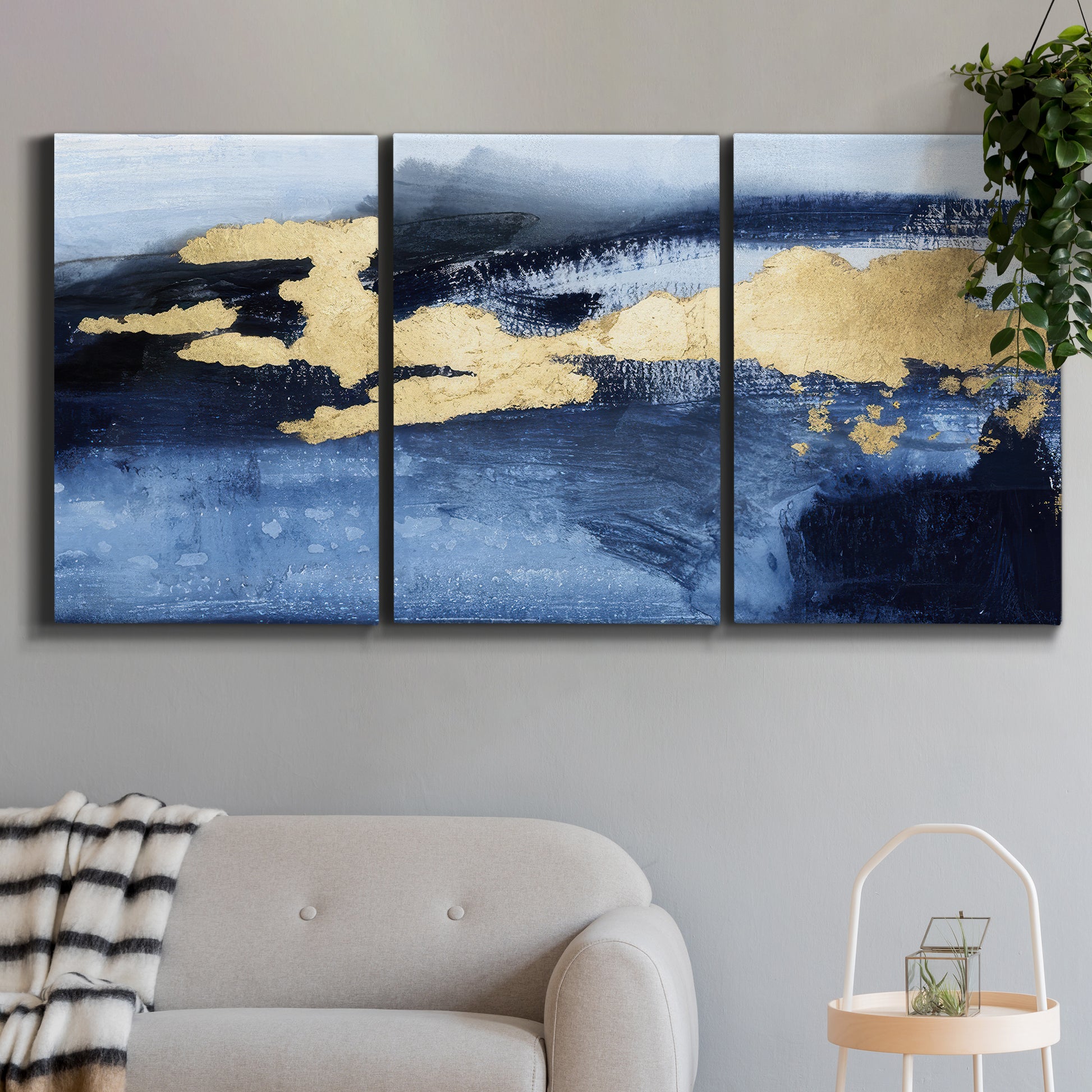 Three-panel canvas wall art featuring coastal shoreline with warm light, displayed in a modern living room above a sofa.