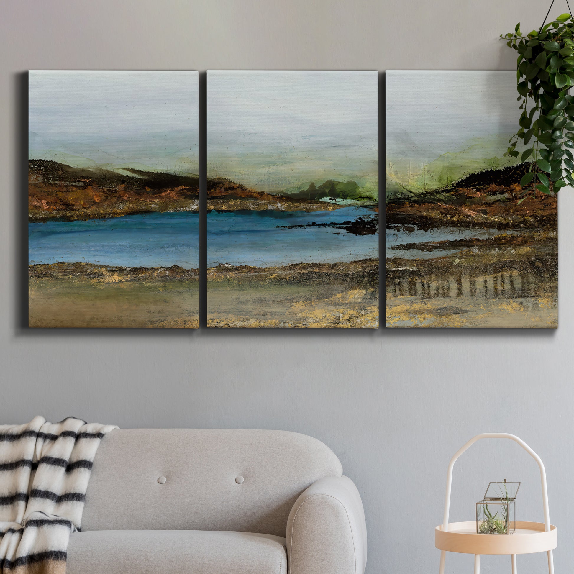 Three-panel canvas wall art featuring peaceful lakeside shoreline landscape, displayed in a modern living room above a sofa.