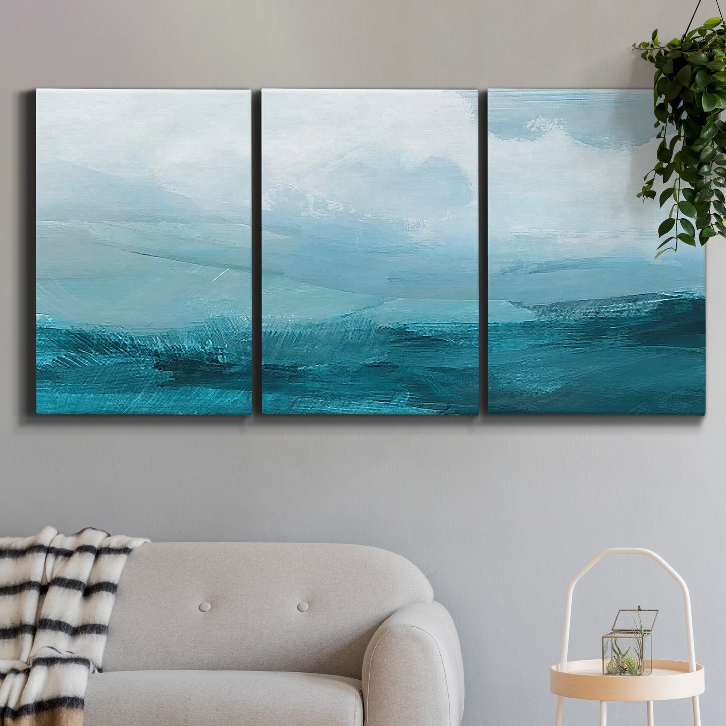 Three-panel canvas wall art featuring vertical coastal elements with rising light, displayed in a modern living room above a sofa.