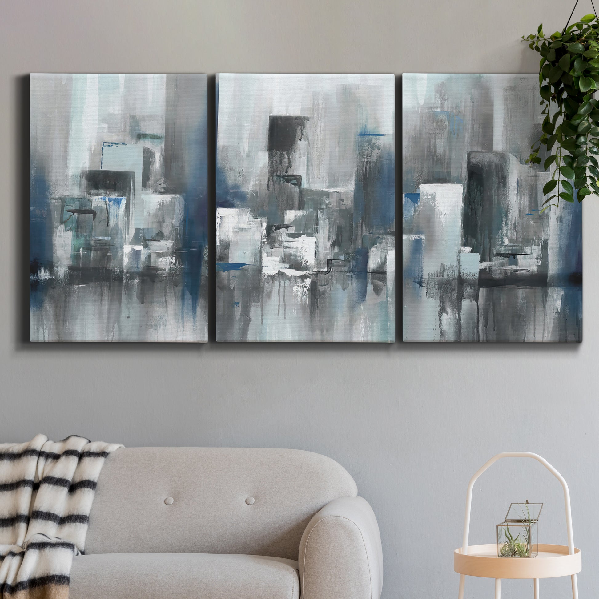 Three-panel canvas wall art featuring urban cityscape rendered in blue tones, displayed in a modern living room above a sofa.