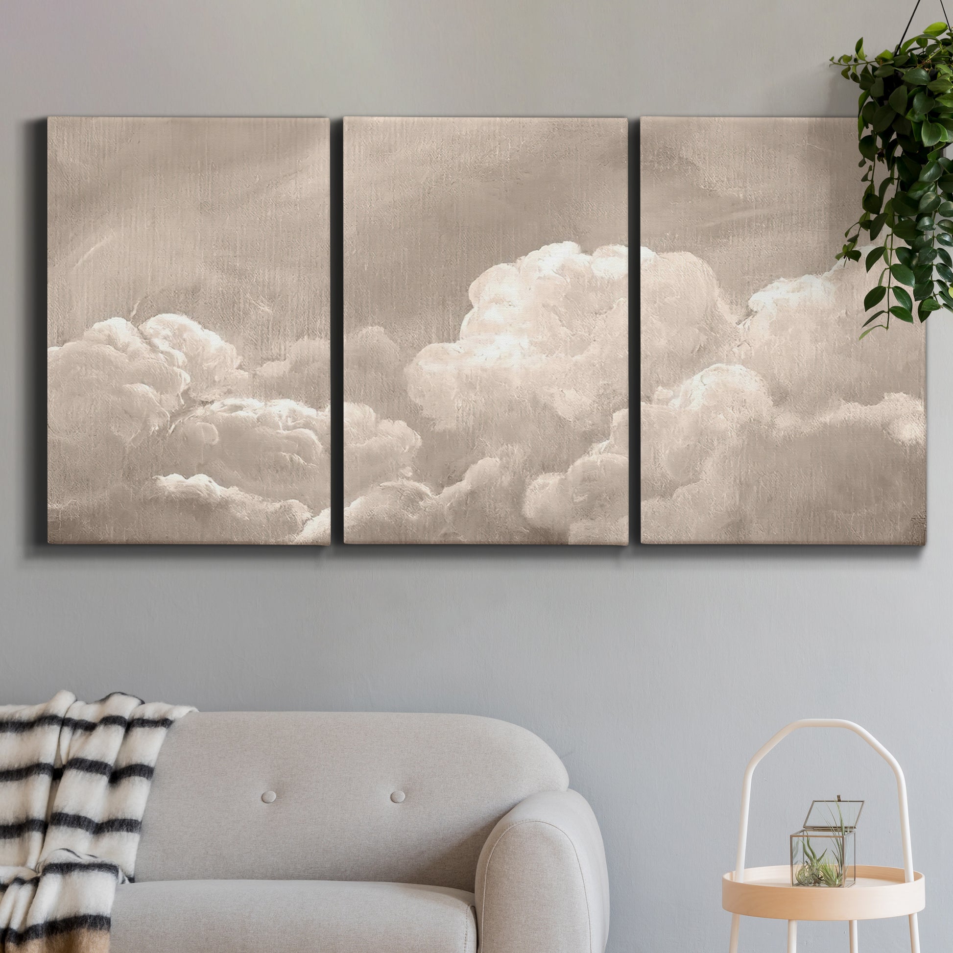 Three-panel canvas wall art featuring soft whimsical cloudscape, displayed in a modern living room above a sofa.