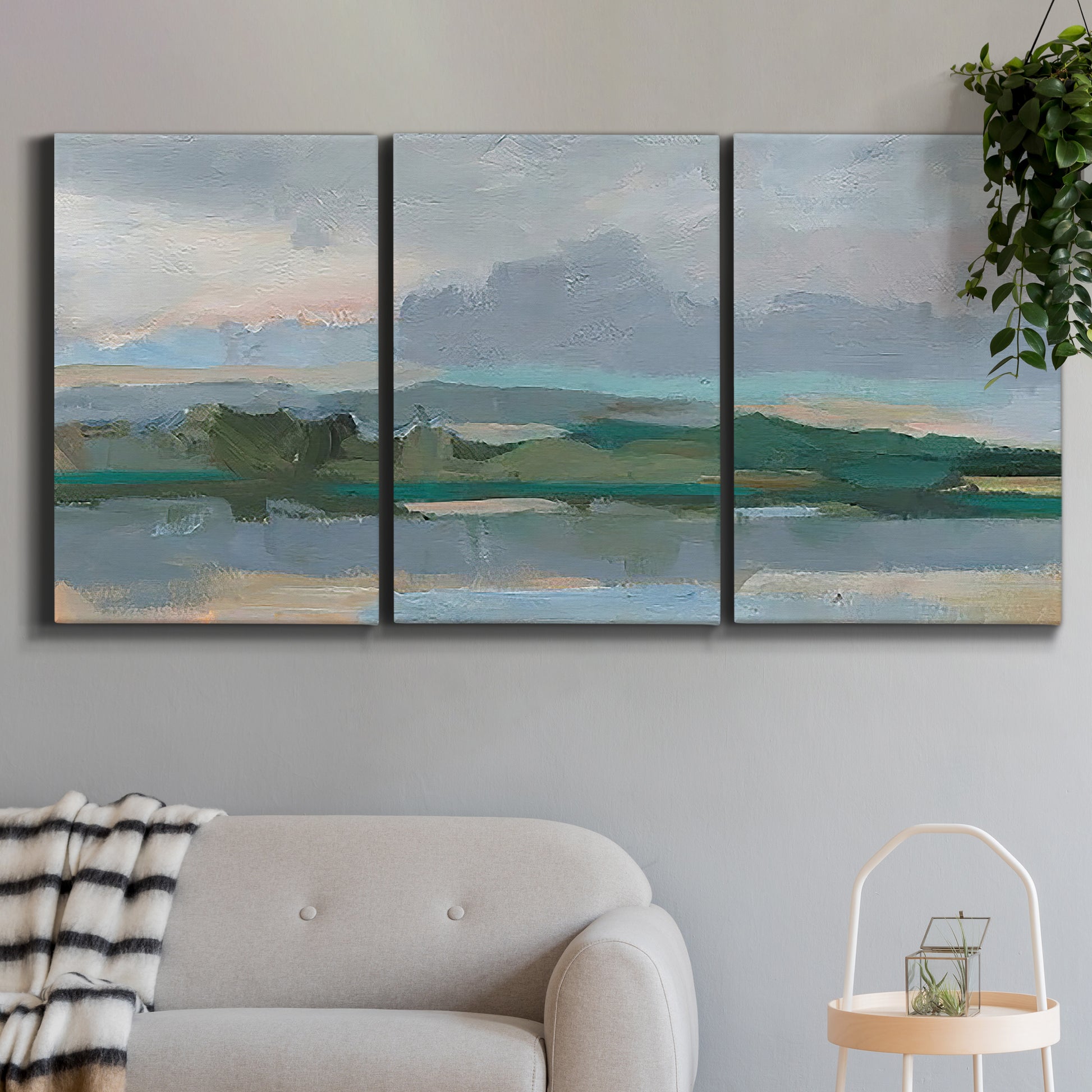 Three-panel canvas wall art featuring twilight landscape with fading light, displayed in a modern living room above a sofa.