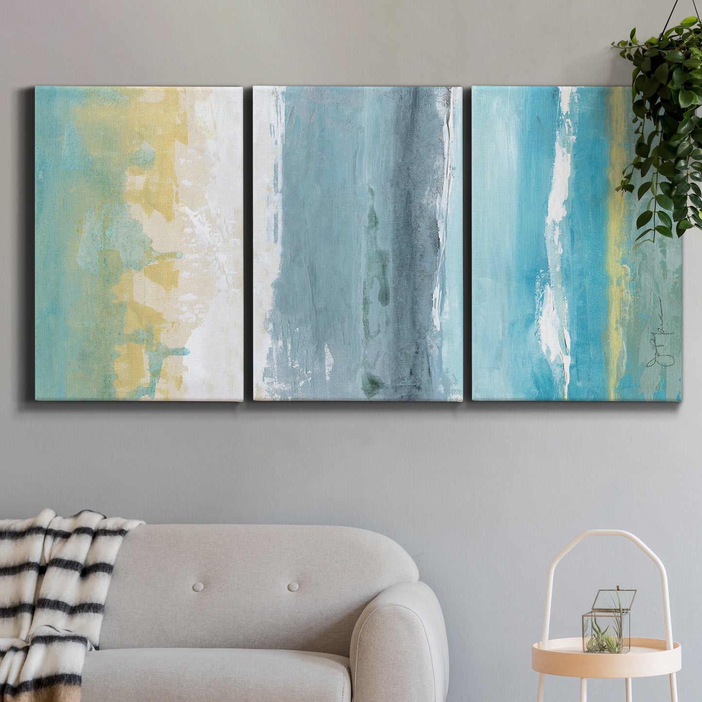 Three-panel canvas wall art featuring abstract coastal beach textures, displayed in a modern living room above a sofa.