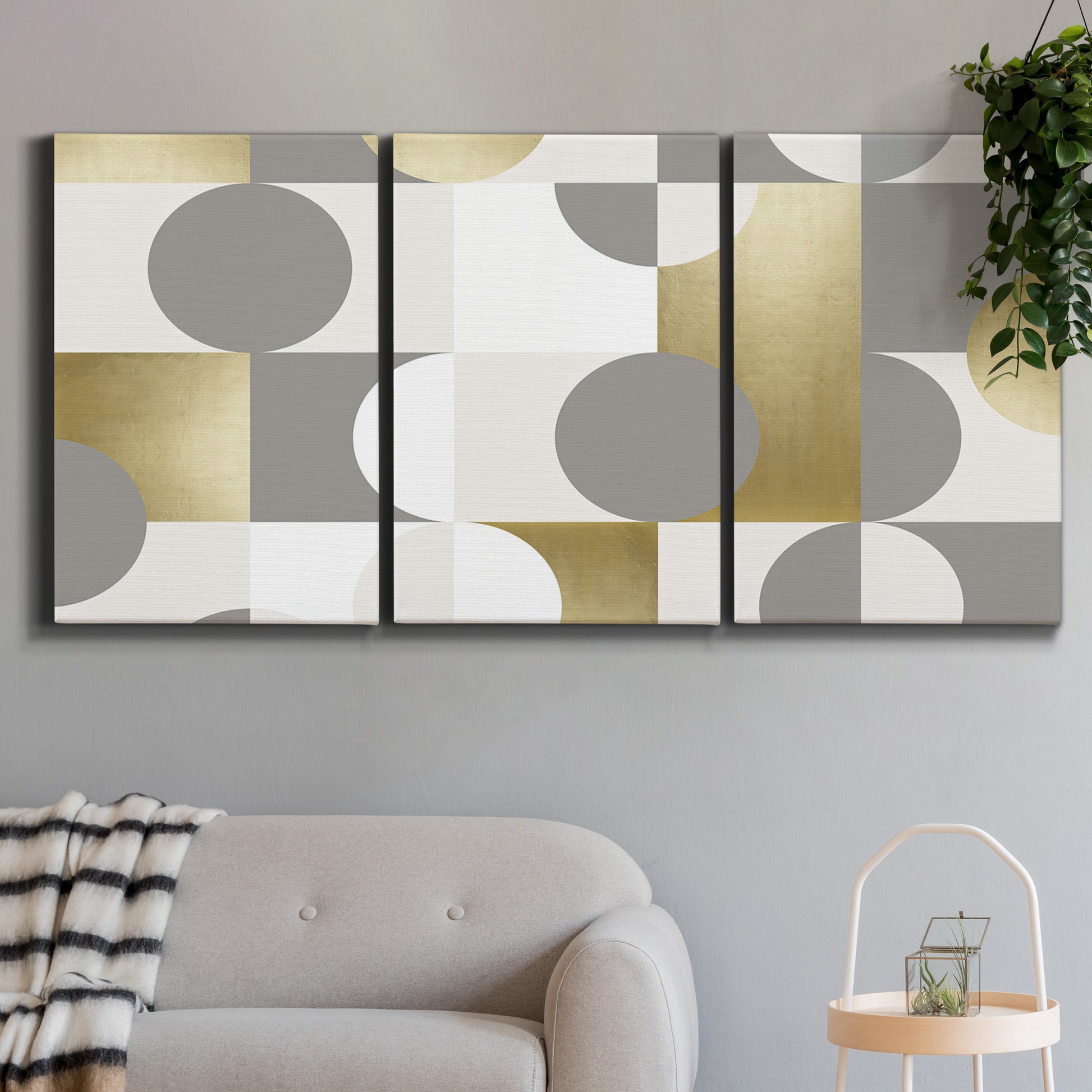 Three-panel canvas wall art featuring geometric gold abstract reflections, displayed in a modern living room above a sofa.