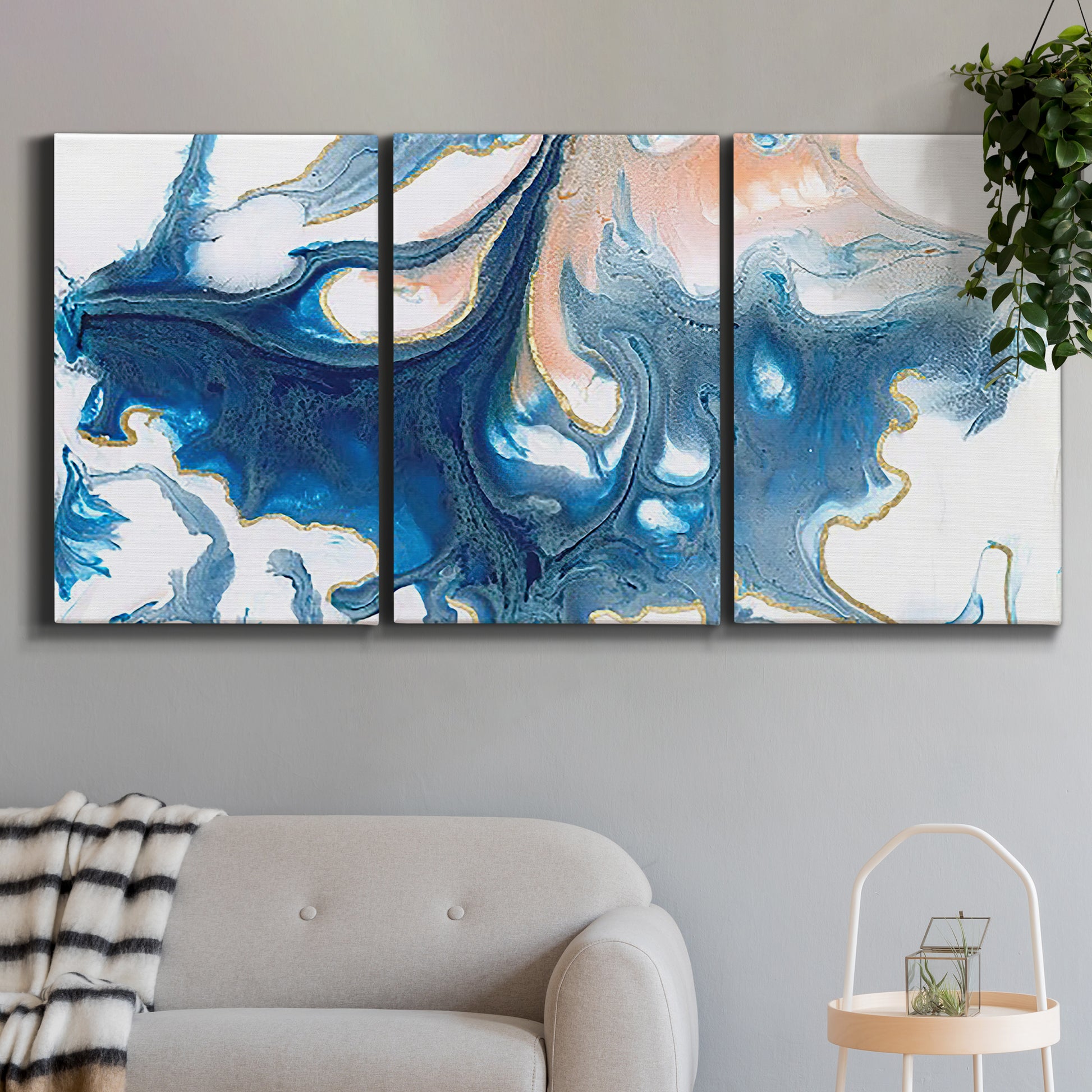 Three-panel canvas wall art featuring flowing blue abstract movement, displayed in a modern living room above a sofa.