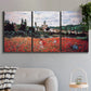Three-panel canvas wall art featuring poppy field beside village landscape, displayed in a modern living room above a sofa.