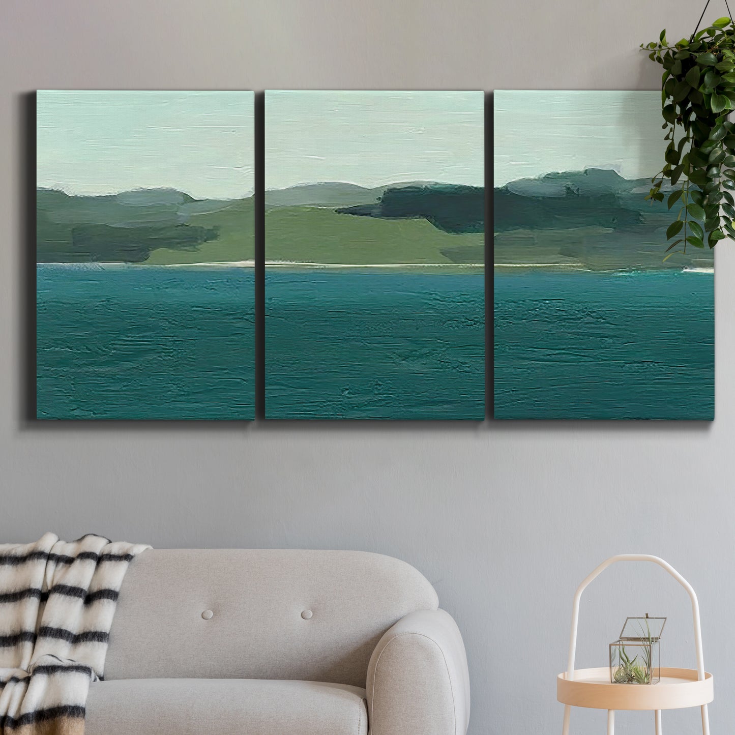 Three-panel canvas wall art featuring calm lake water under open sky, displayed in a modern living room above a sofa.