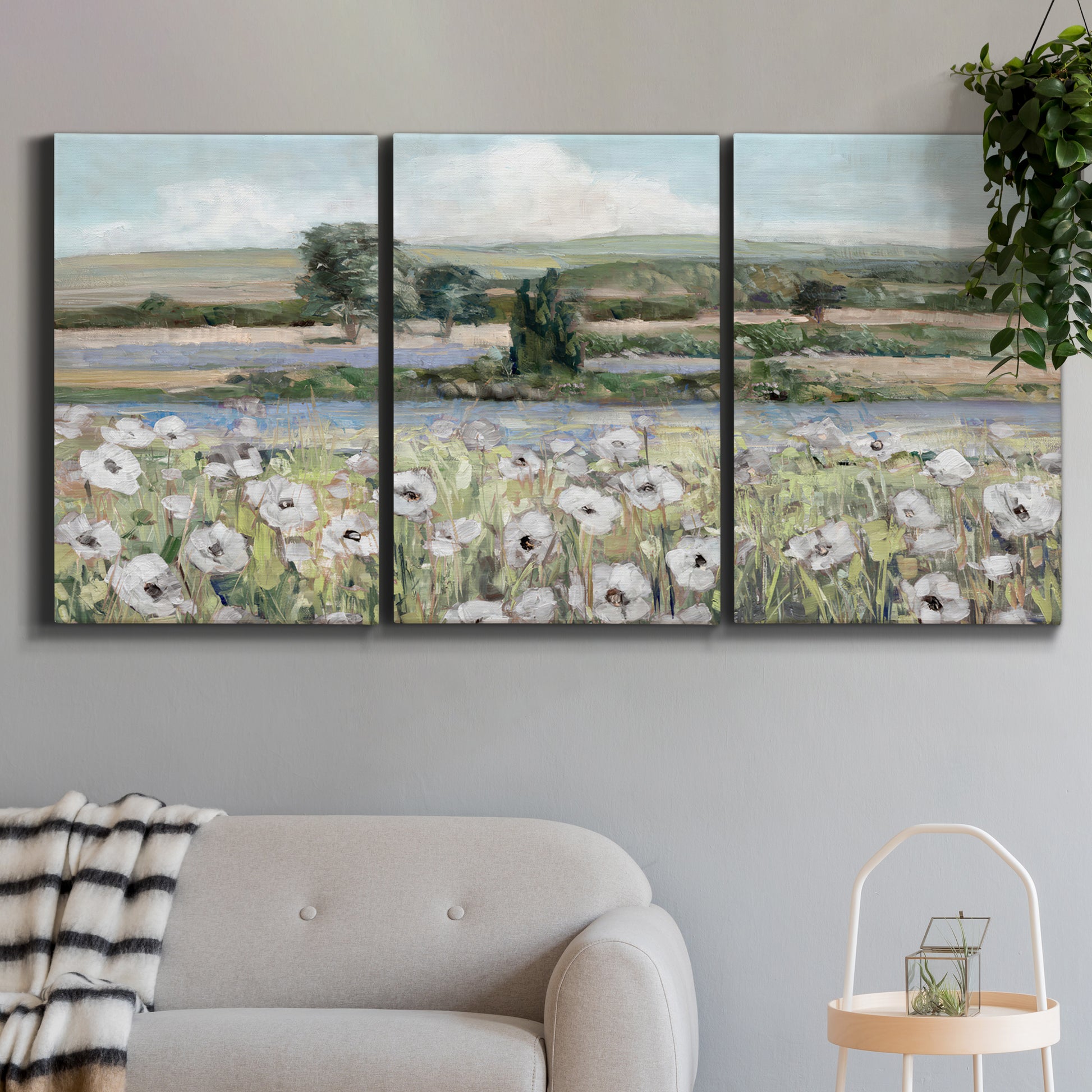 Three-panel canvas wall art featuring vintage poppy filled valley, displayed in a modern living room above a sofa.