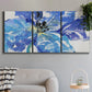 Three-panel canvas wall art featuring blue floral botanical close up, displayed in a modern living room above a sofa.