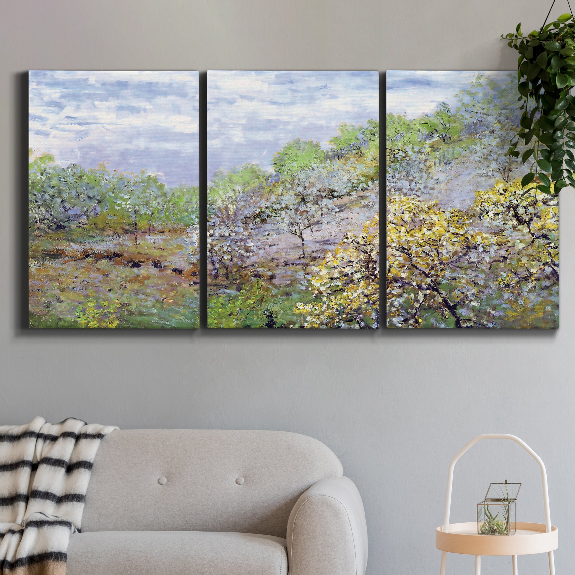 Three-panel canvas wall art featuring spring orchard in full bloom, displayed in a modern living room above a sofa.