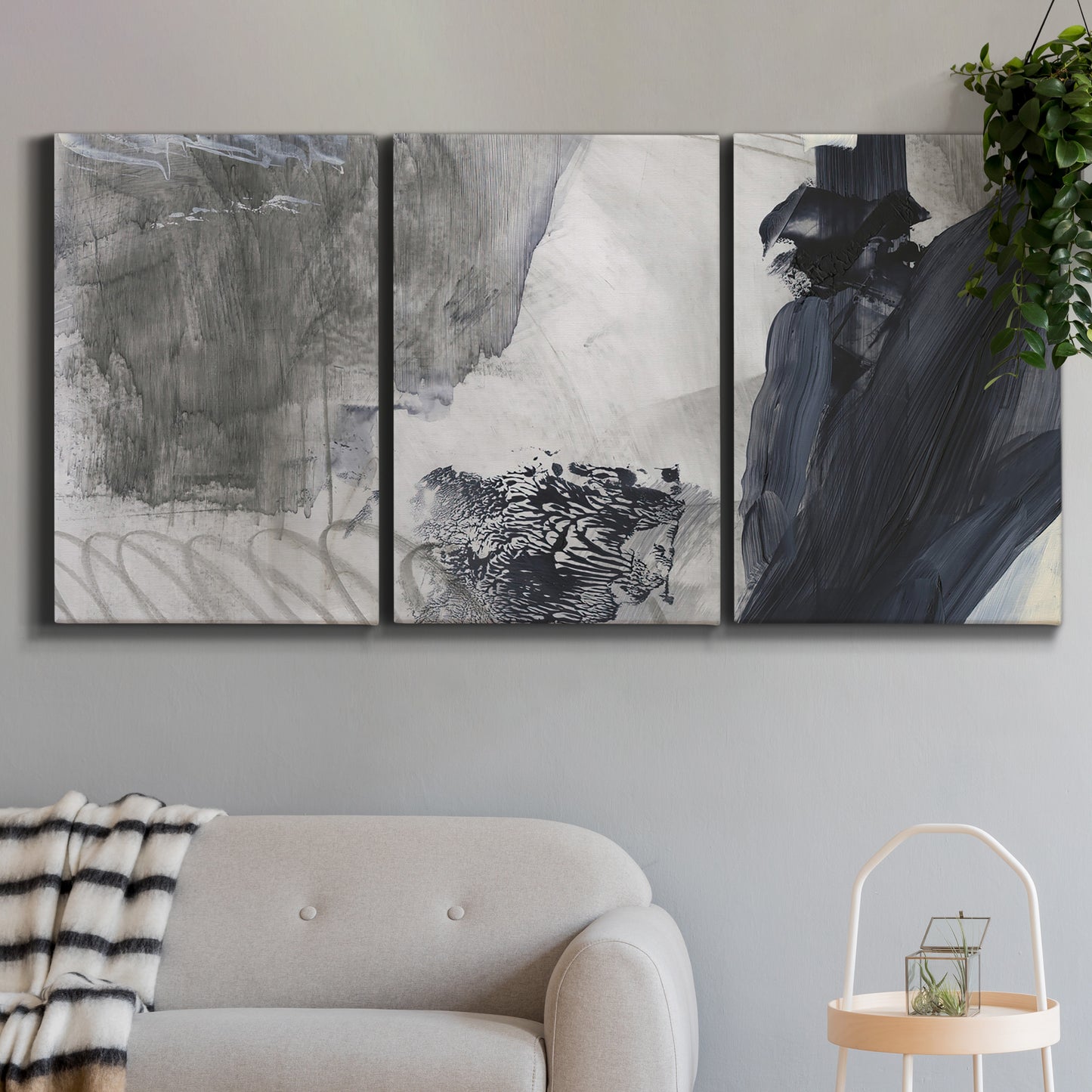 Three-panel canvas wall art featuring dark abstract atmospheric landscape, displayed in a modern living room above a sofa.