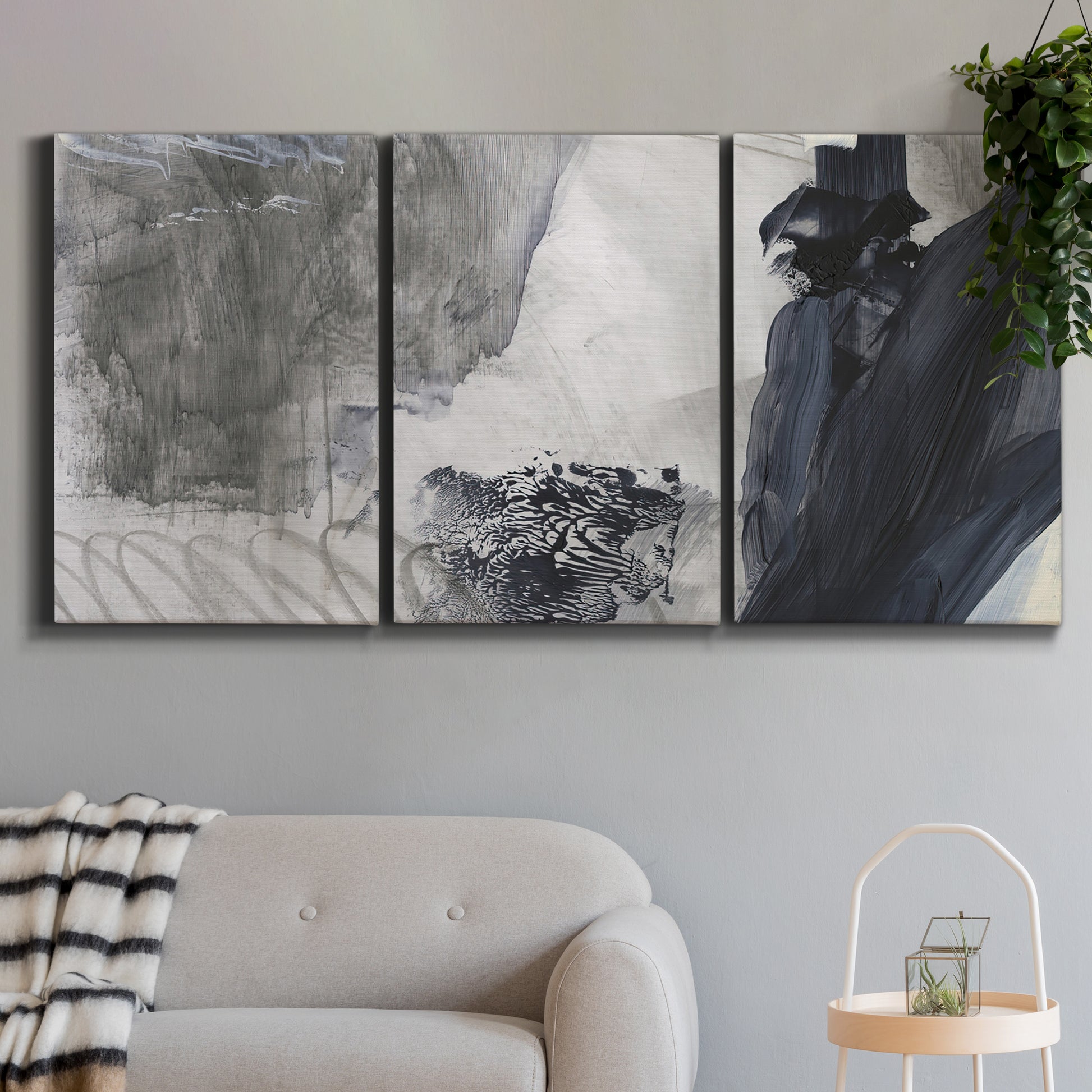 Three-panel canvas wall art featuring dark abstract atmospheric landscape, displayed in a modern living room above a sofa.