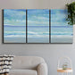 Three-panel canvas wall art featuring rolling ocean surf along shoreline, displayed in a modern living room above a sofa.