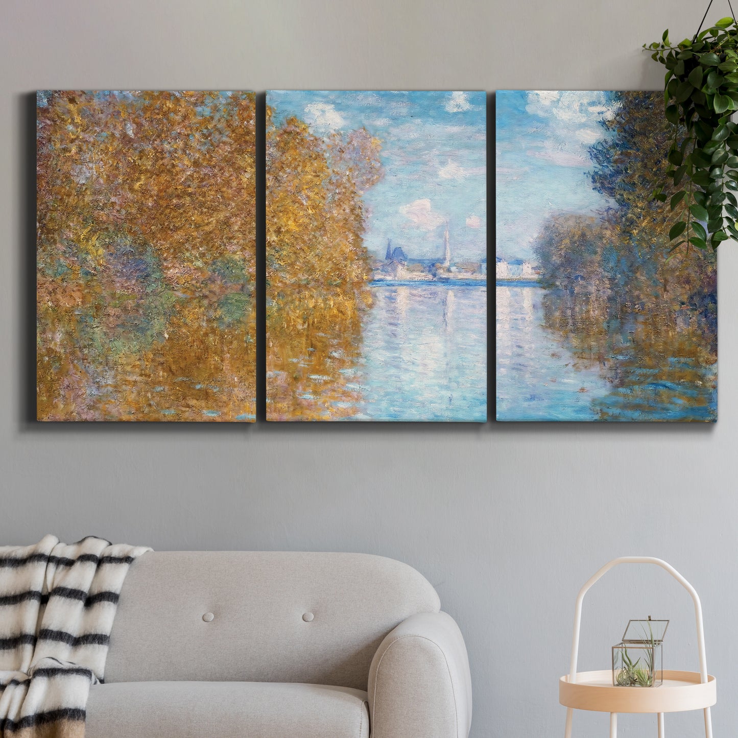 Three-panel canvas wall art featuring autumn landscape with glowing foliage, displayed in a modern living room above a sofa.