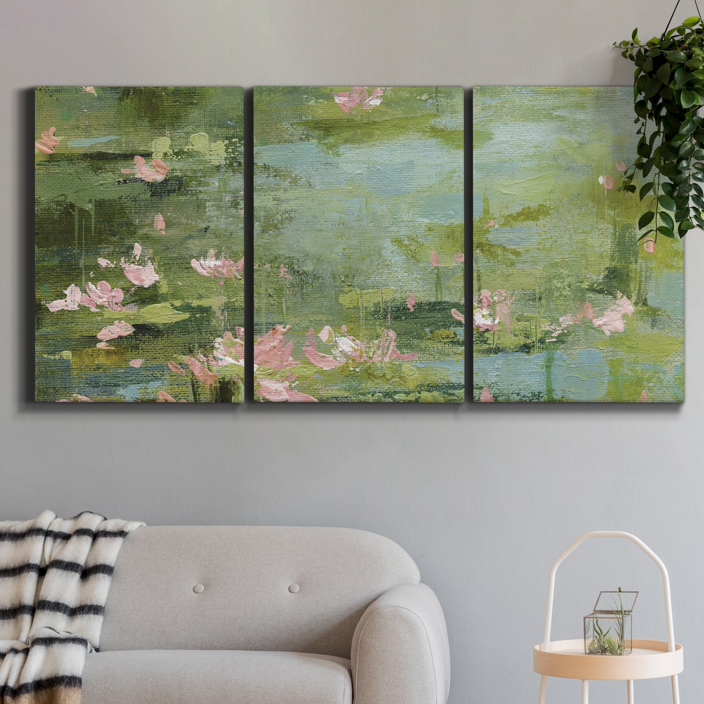 Three-panel canvas wall art featuring muted water lily pond, displayed in a modern living room above a sofa.