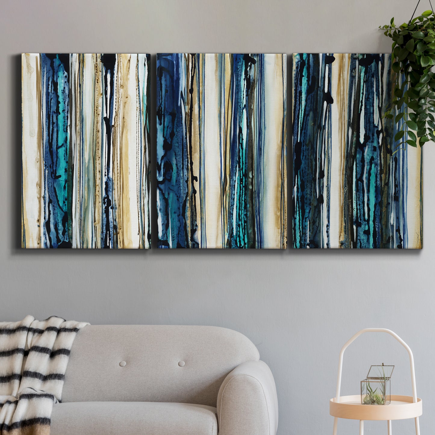 Three-panel canvas wall art featuring vertical blue abstract streaks, displayed in a modern living room above a sofa.
