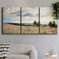 Three-panel canvas wall art featuring wildflowers across tuscan landscape, displayed in a modern living room above a sofa.