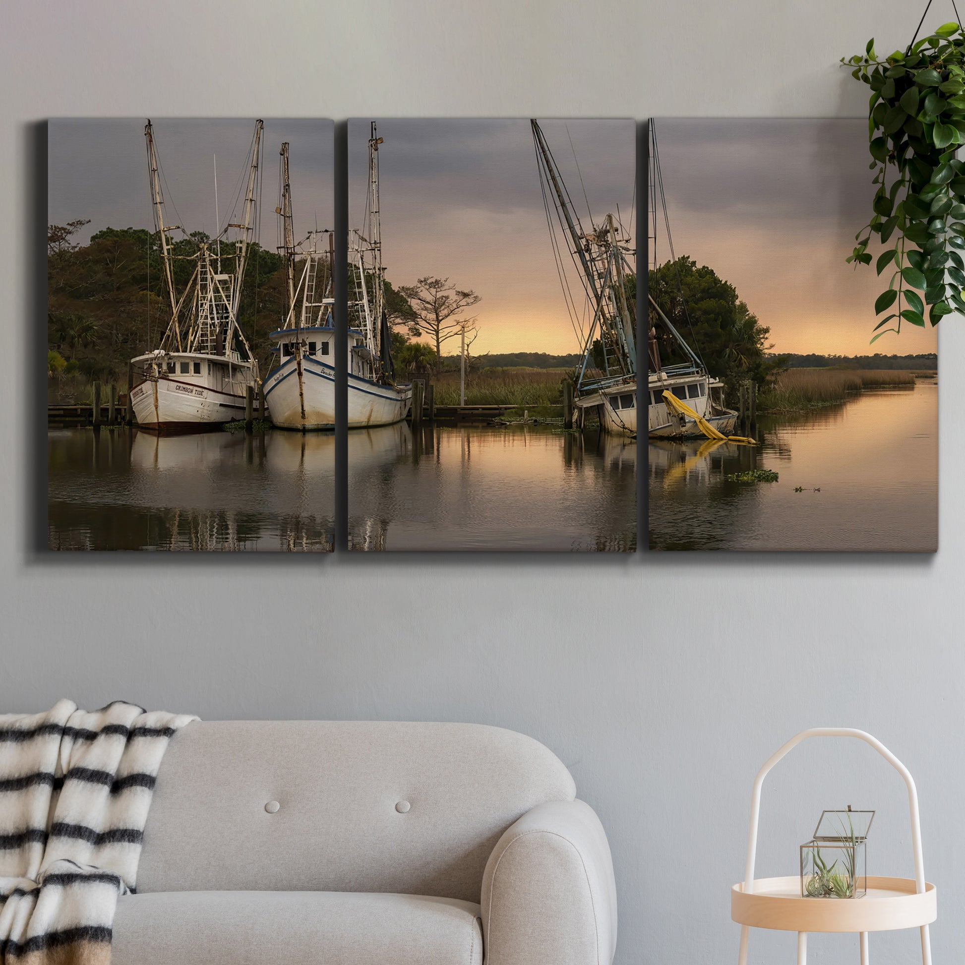 Three-panel canvas wall art featuring fishing trawlers on working harbor, displayed in a modern living room above a sofa.