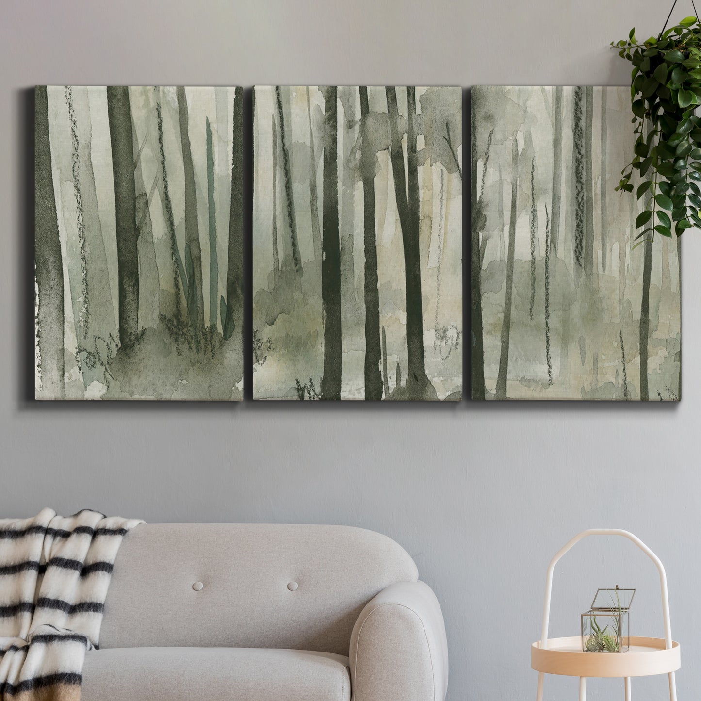Three-panel canvas wall art featuring wooded forest path watercolor, displayed in a modern living room above a sofa.