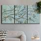 Three-panel canvas wall art featuring blue sky with flowering branches, displayed in a modern living room above a sofa.