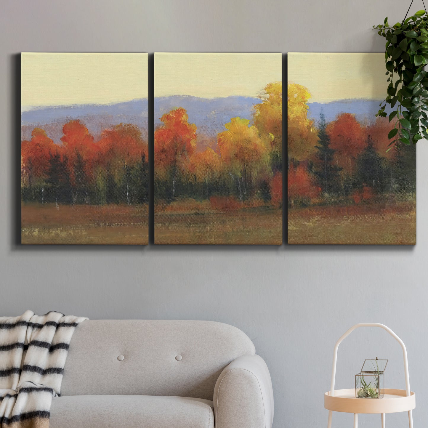 Three-panel canvas wall art featuring autumn landscape changing foliage, displayed in a modern living room above a sofa.
