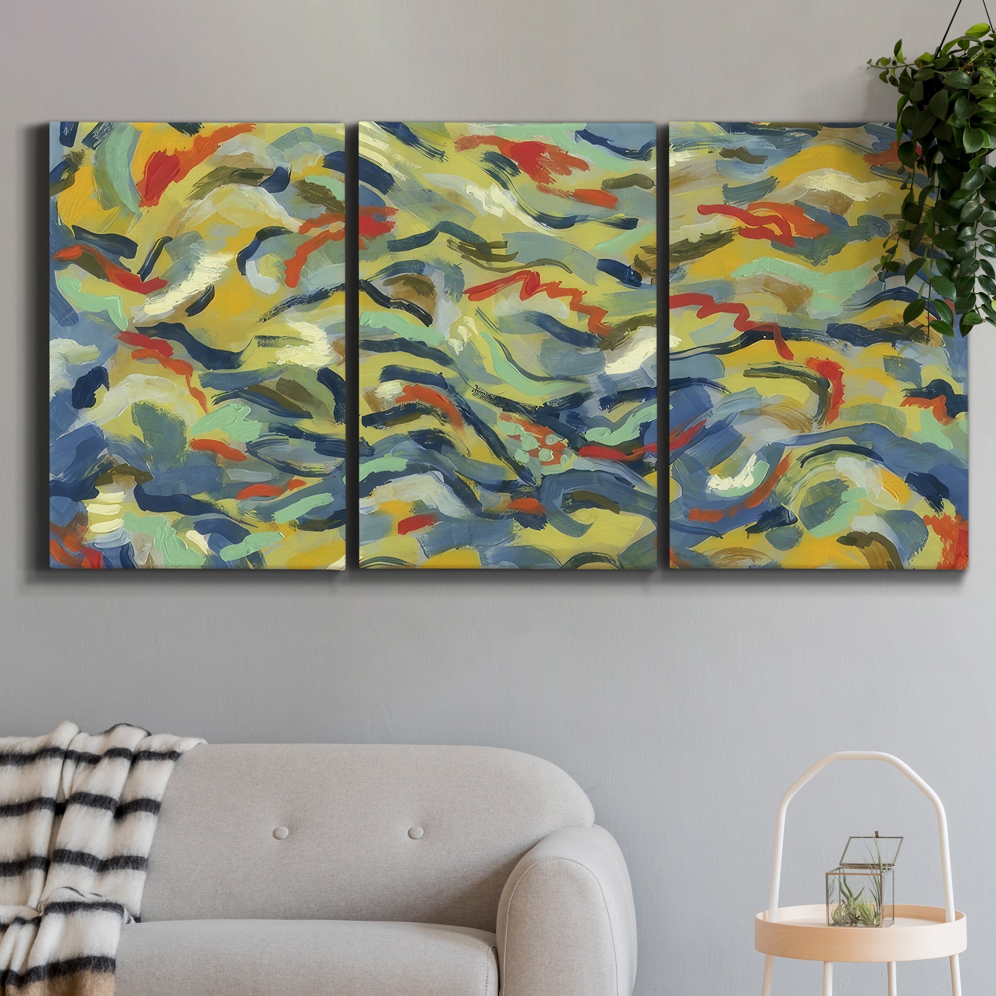 Three-panel canvas wall art featuring colorful abstract river like motion, displayed in a modern living room above a sofa.