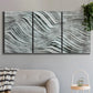 Three-panel canvas wall art featuring coastal shoreline with gentle surf, displayed in a modern living room above a sofa.