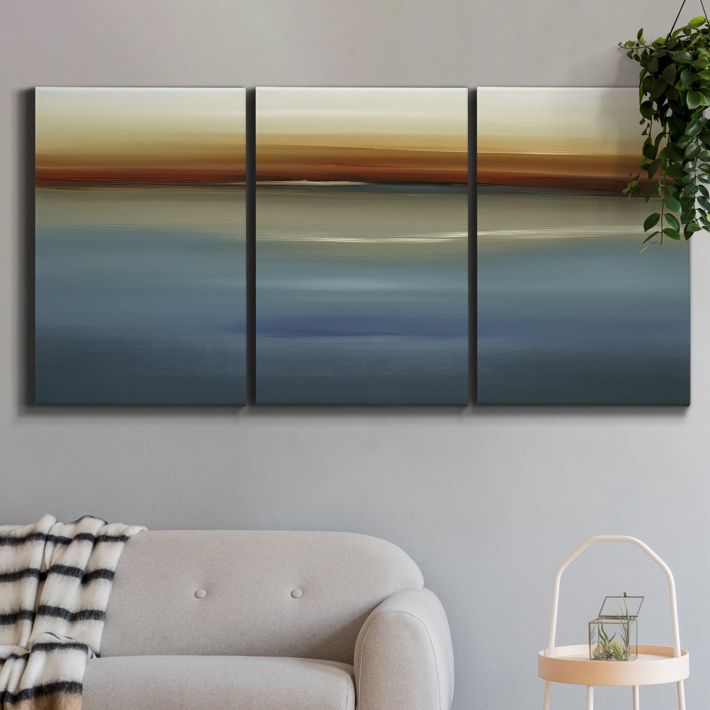 Three-panel canvas wall art featuring horizontal abstract coastal color bands, displayed in a modern living room above a sofa.