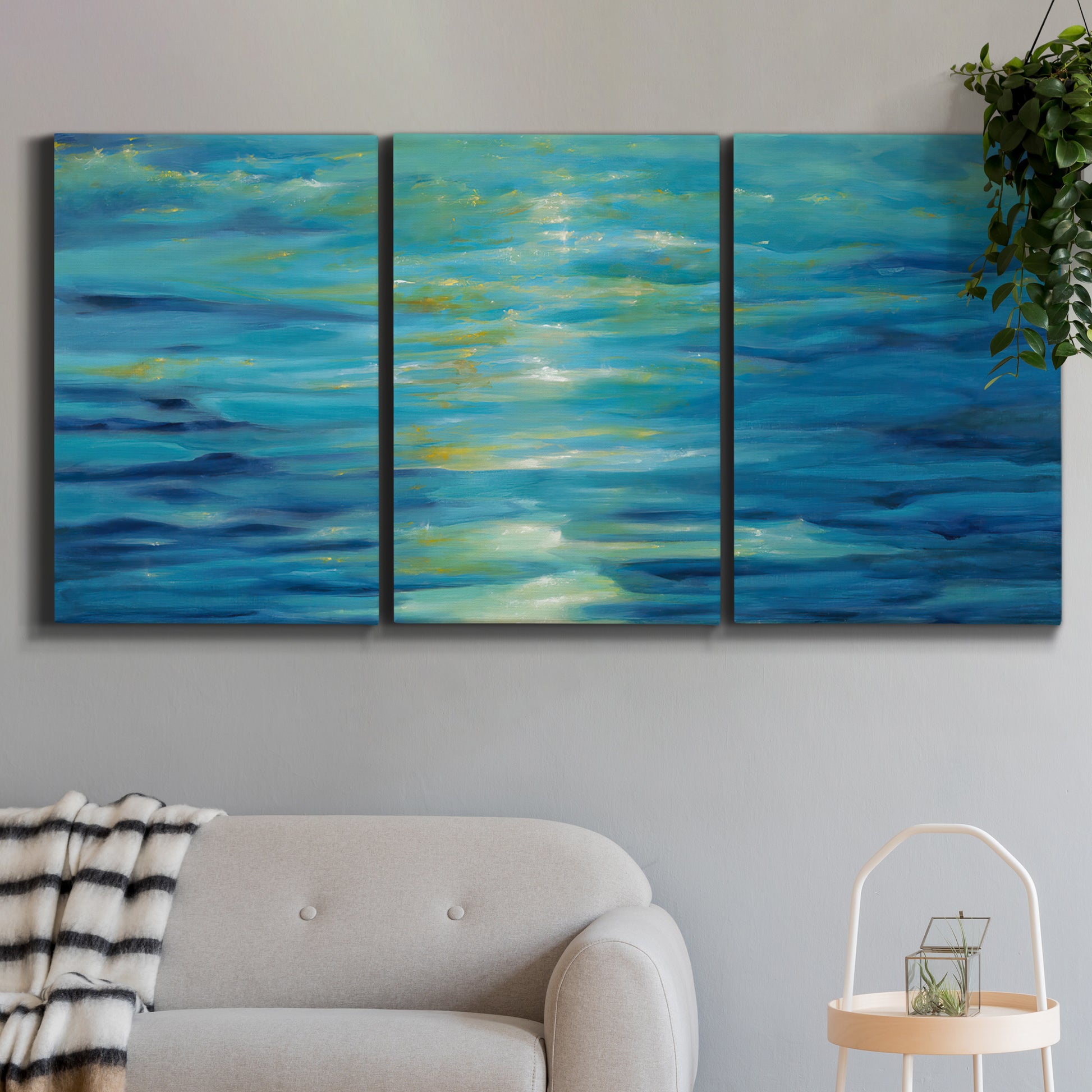 Three-panel canvas wall art featuring deep blue ocean water abstraction, displayed in a modern living room above a sofa.