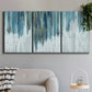 Three-panel canvas wall art featuring wide pastoral valley landscape, displayed in a modern living room above a sofa.