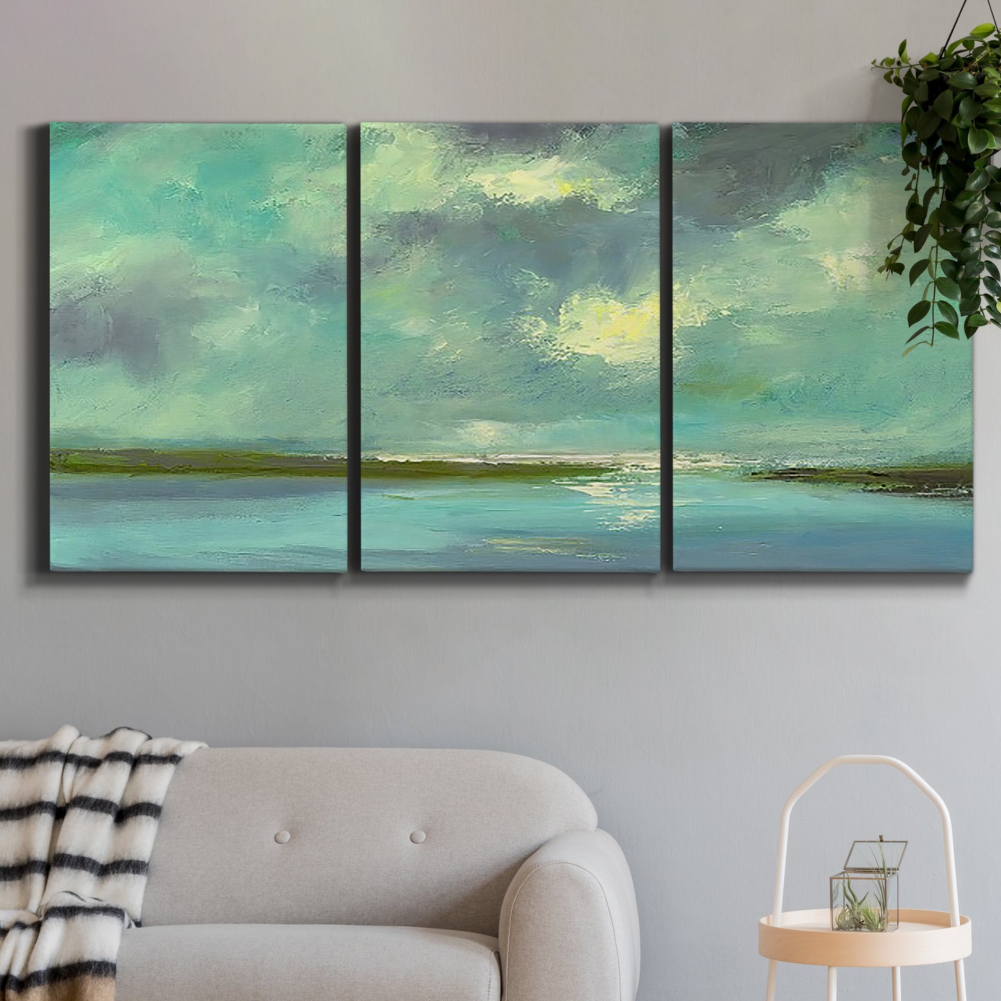 Three-panel canvas wall art featuring still lagoon water beneath open sky, displayed in a modern living room above a sofa.