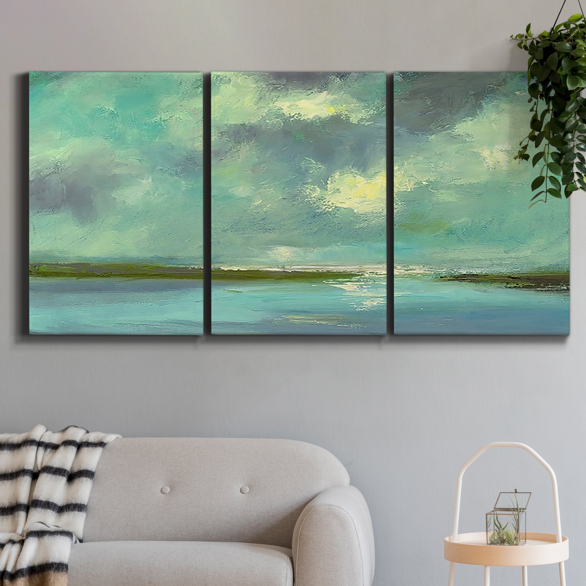Three-panel canvas wall art featuring still lagoon water beneath open sky, displayed in a modern living room above a sofa.