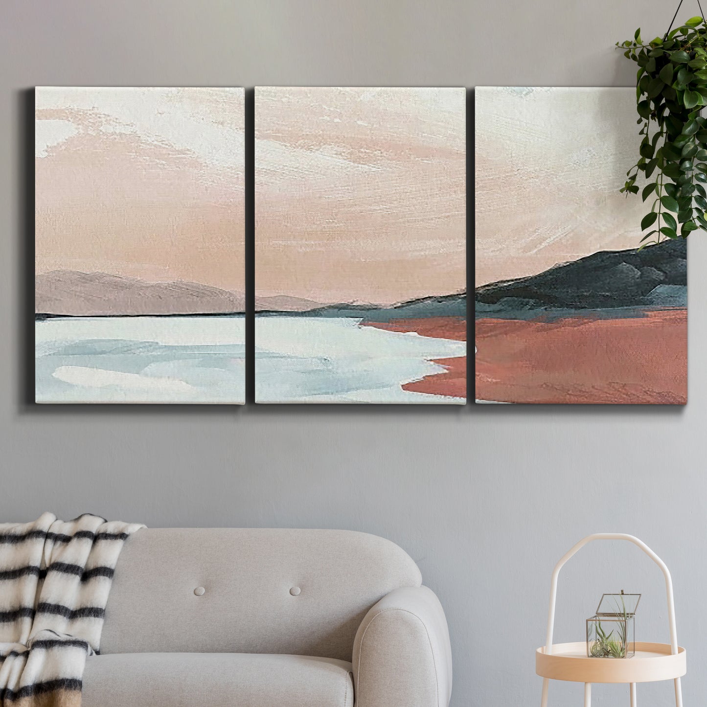 Three-panel canvas wall art featuring quiet coastline with distant horizon, displayed in a modern living room above a sofa.