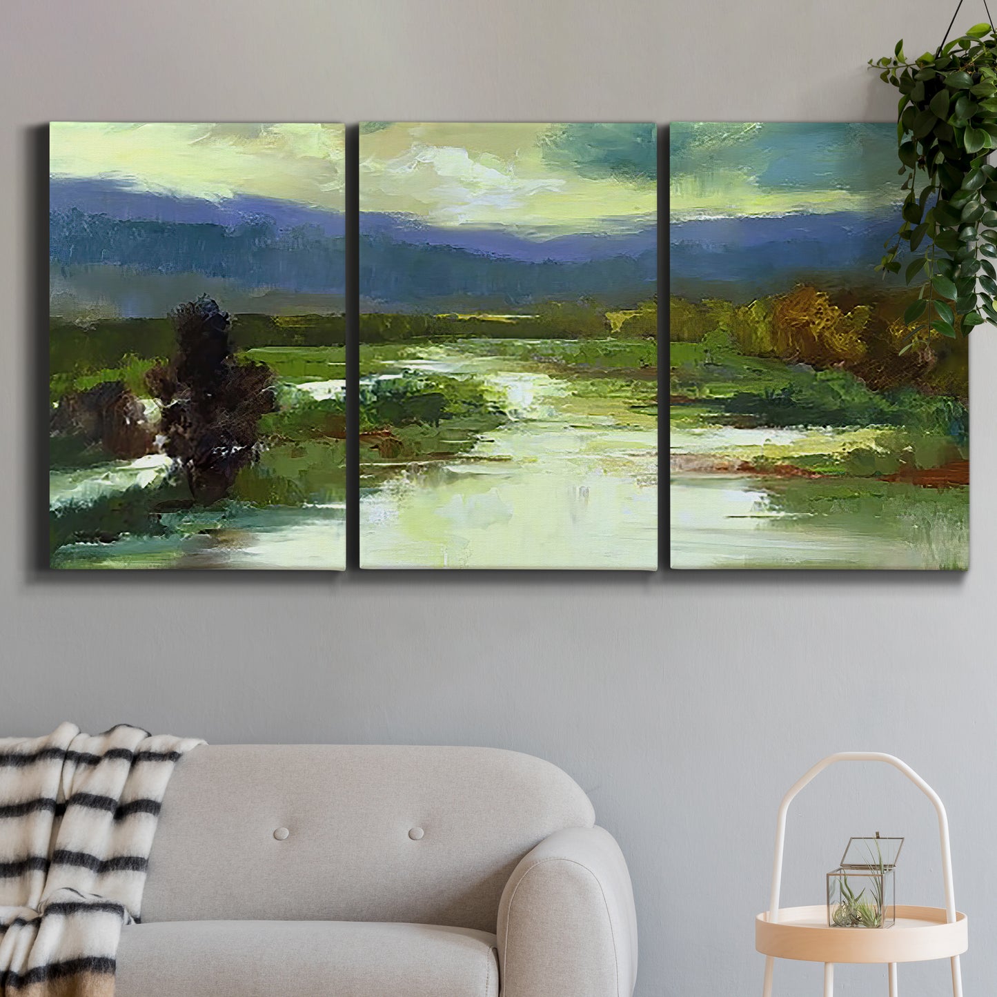 Three-panel canvas wall art featuring open meadow landscape with distant hills, displayed in a modern living room above a sofa.
