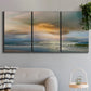 Three-panel canvas wall art featuring tranquil beach at sunset, displayed in a modern living room above a sofa.