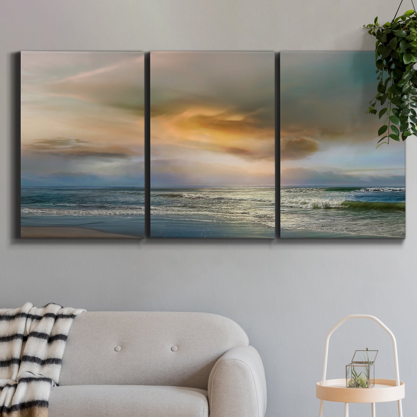 Three-panel canvas wall art featuring tranquil beach at sunset, displayed in a modern living room above a sofa.