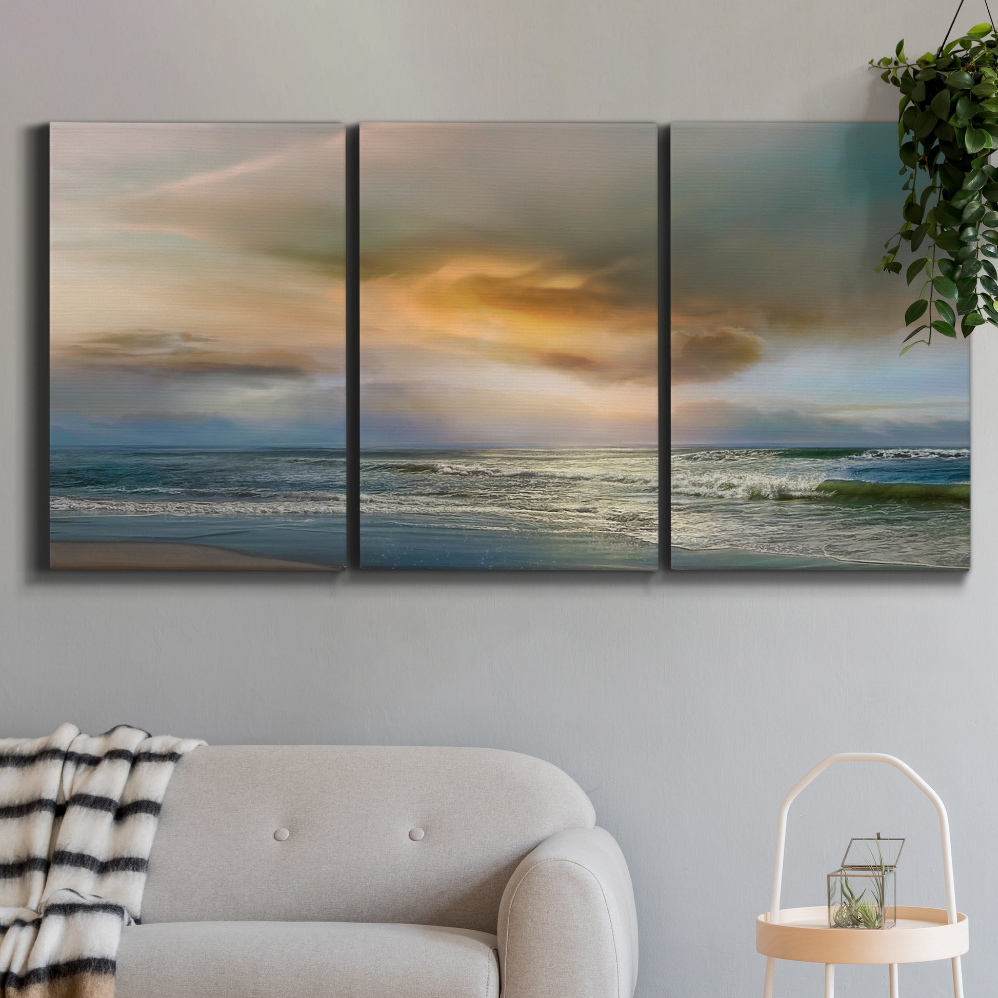 Three-panel canvas wall art featuring tranquil beach at sunset, displayed in a modern living room above a sofa.