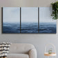 Three-panel canvas wall art featuring grayscale seascape with horizon, displayed in a modern living room above a sofa.