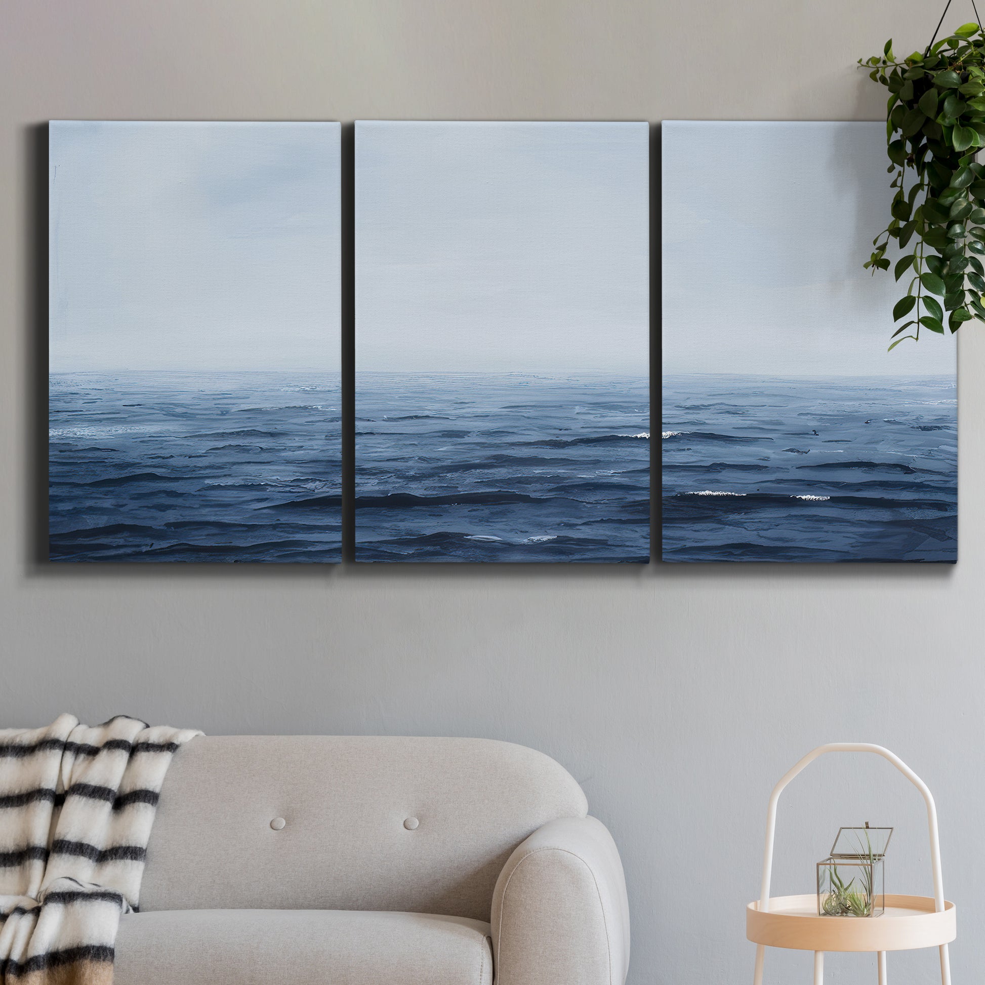 Three-panel canvas wall art featuring grayscale seascape with horizon, displayed in a modern living room above a sofa.