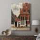 Canvas art print featuring a calm exterior scene with buildings and subtle activity displayed in a modern interior space.