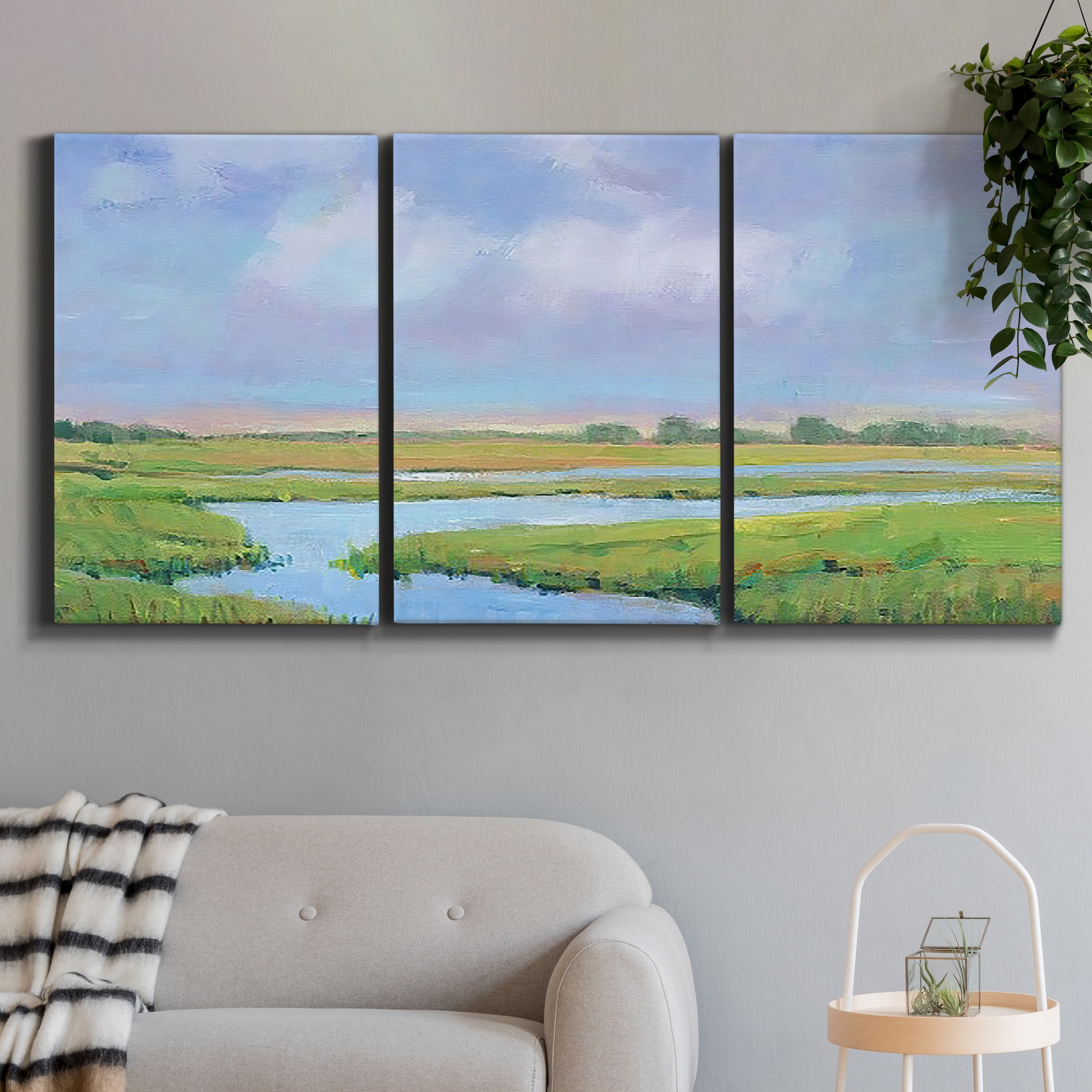 Three-panel canvas wall art featuring summer marshland with tall grasses, displayed in a modern living room above a sofa.