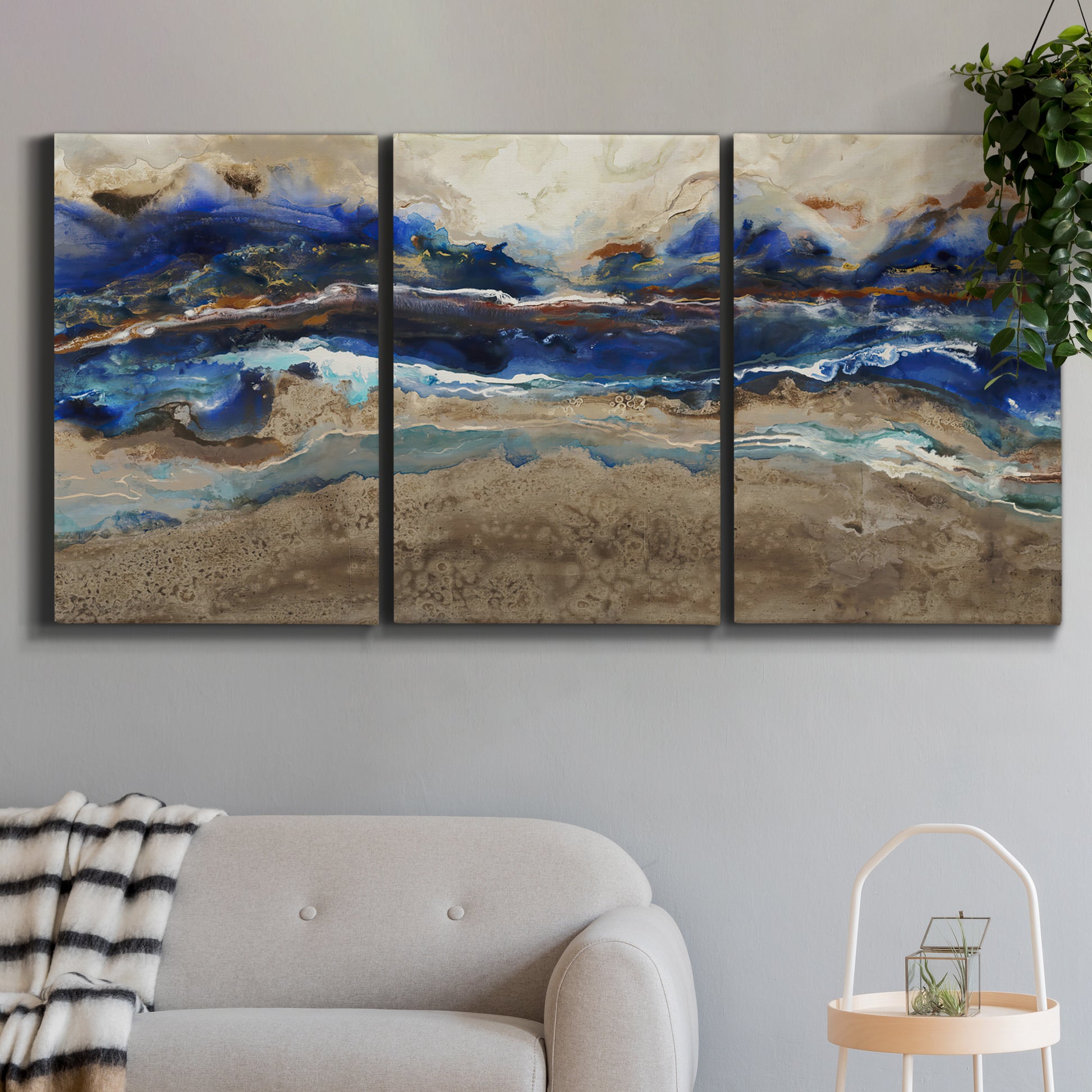 Three-panel canvas wall art featuring abstract coastal jewel toned composition, displayed in a modern living room above a sofa.