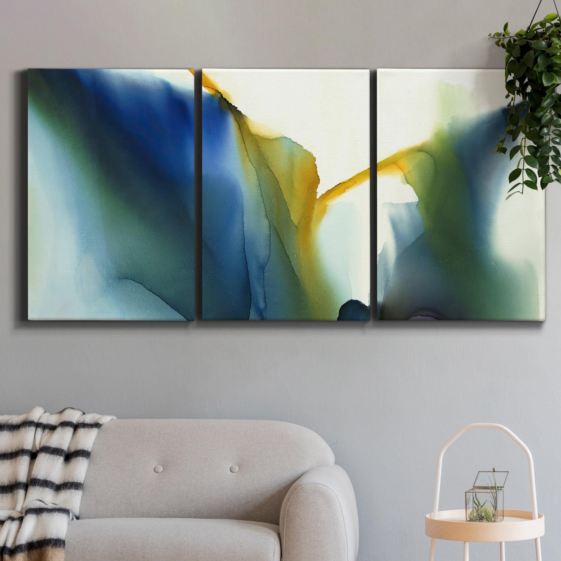 Three-panel canvas wall art featuring soft abstract mask like forms, displayed in a modern living room above a sofa.