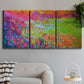 Three-panel canvas wall art featuring abstract meadow inspired color fields, displayed in a modern living room above a sofa.