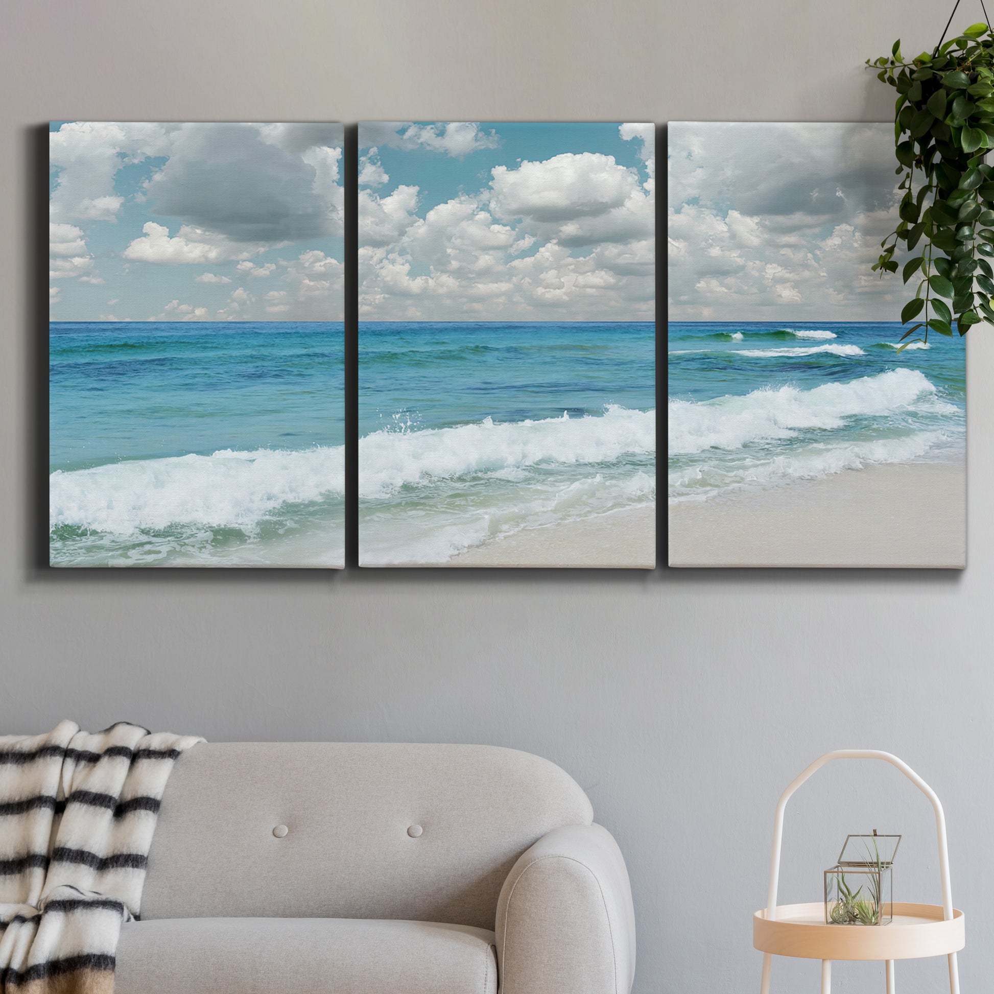 Three-panel canvas wall art featuring tropical beach scene with turquoise water, displayed in a modern living room above a sofa.