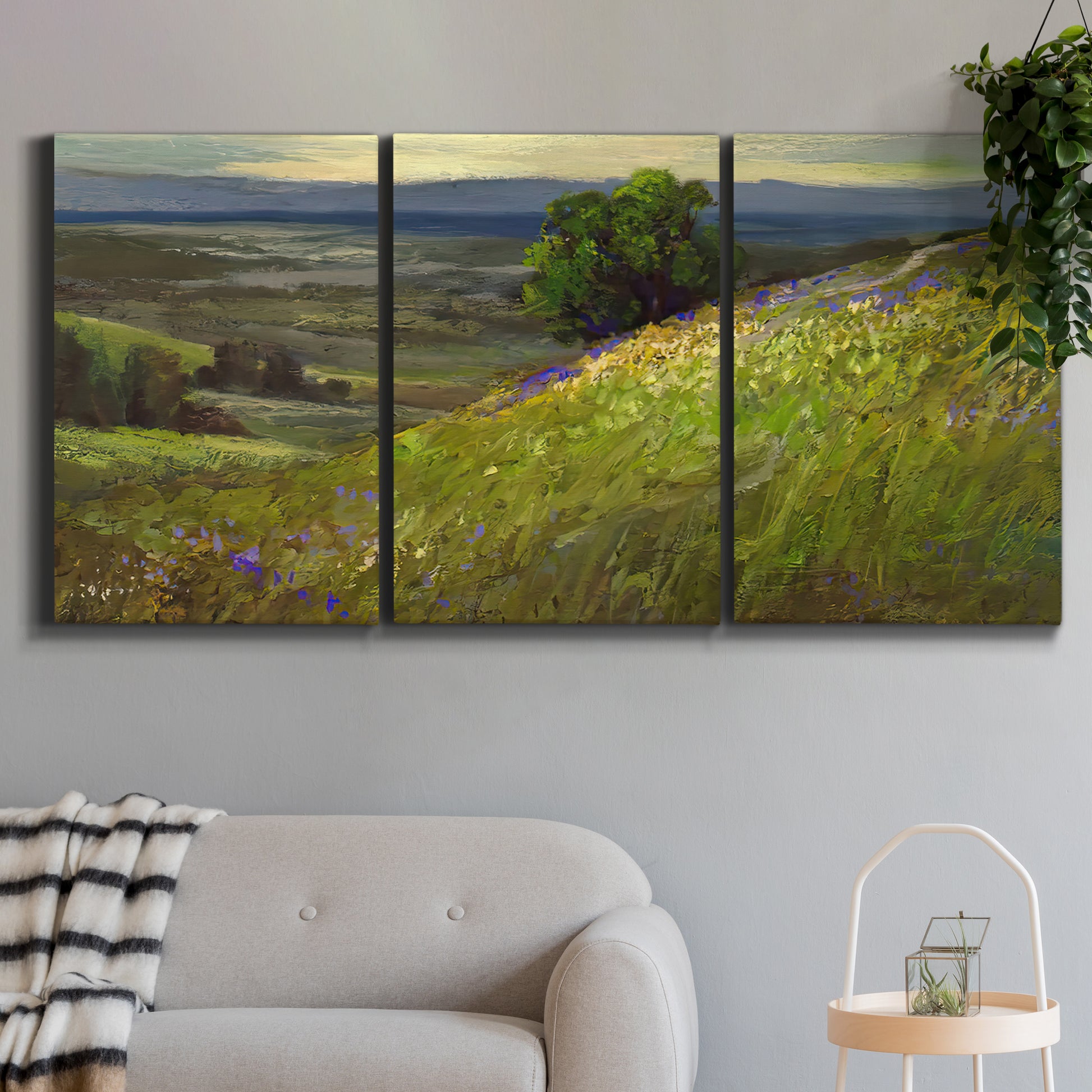 Three-panel canvas wall art featuring winding path through rolling hills, displayed in a modern living room above a sofa.
