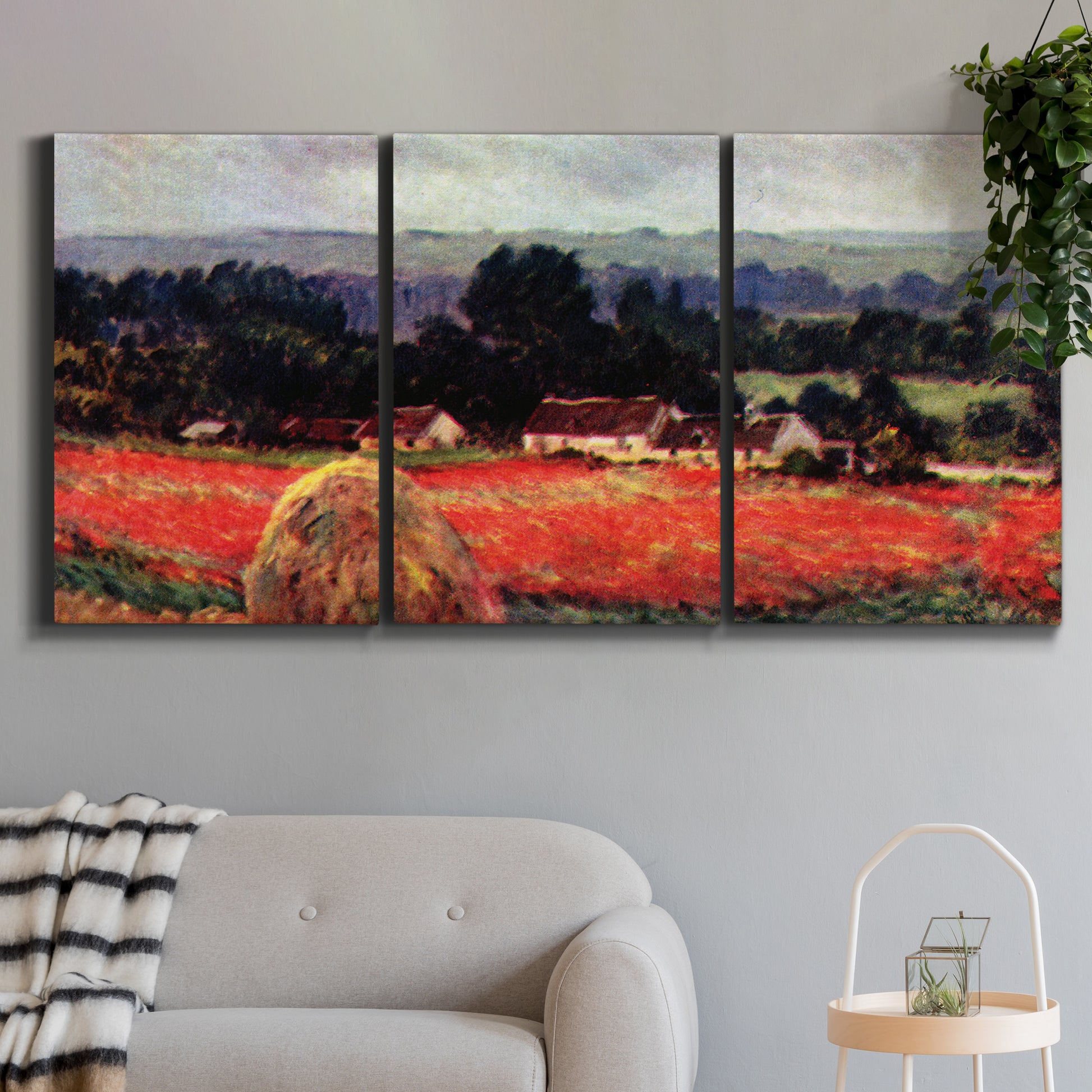 Three-panel canvas wall art featuring red poppy field near barn, displayed in a modern living room above a sofa.