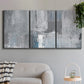 Three-panel canvas wall art featuring cool toned industrial abstract blues, displayed in a modern living room above a sofa.